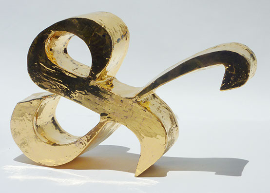 A golden reflective sculpture of an ampsersand.