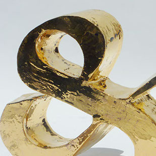 A golden reflective sculpture of an ampsersand.