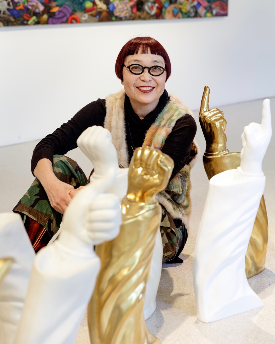 Keiko Fukazawa, she wears glasses and is behind sculptures of arms, Photography by William Short