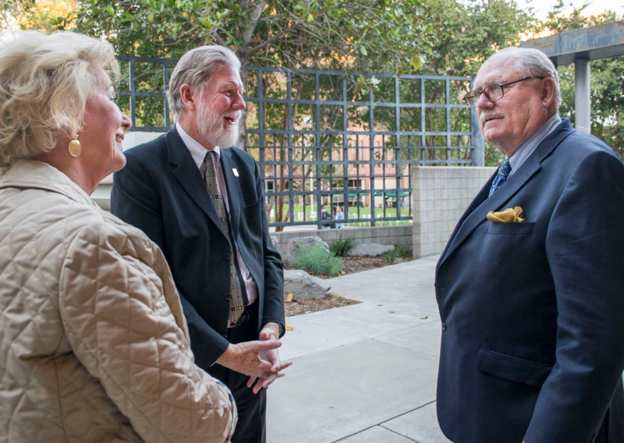 Don B. Huntley in front of the gallery speaking to 2 people