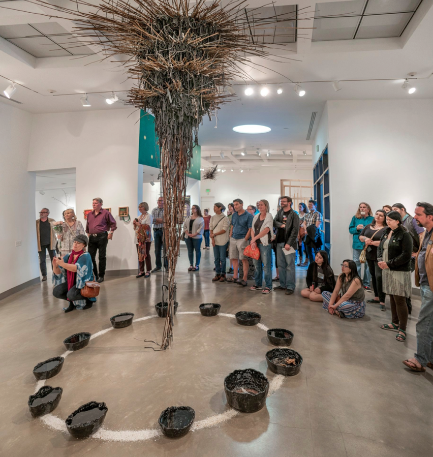 Large Group at the Kellogg University Gallery during a catered Special Event in conjunction with exhibition Artists Talk. St. Broxville Wood: Into the Thicket, 2020 exhibition featuring the center-of-the-room installation by Katie Stubblefield titled Comeuppance. Larger groups require added staff on hand for the protection of artworks on display.