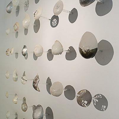 Sabrina Bommarito, "Beauty Within" has several circular objects in shades of white, and brown on clear small polls.