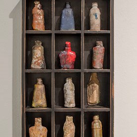 Jan Davids, Fred’s Stash is a shelving unit that has various painted bottles in each spot.