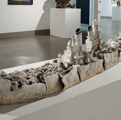 Jon Gariepy, Silence. On a long white rectangle sculpture stand, there is a sculpture that appears to be an old white and grey ship.