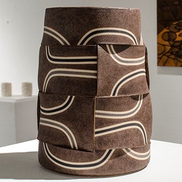 Jose Sierra, "Entre Tejidos Series" brown abstract vase with cream lines, and black lines on top.