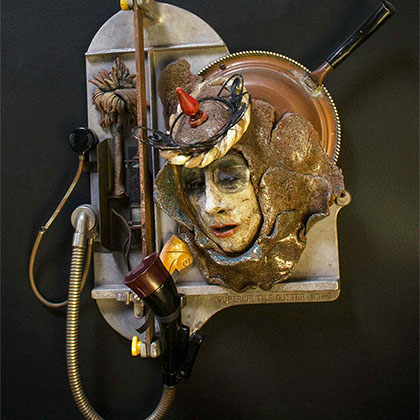 sculpture of the head of a person using an old telephone device; sculpture is made out of assemblage: clay with Ediphone parts, tile cutter and found objects