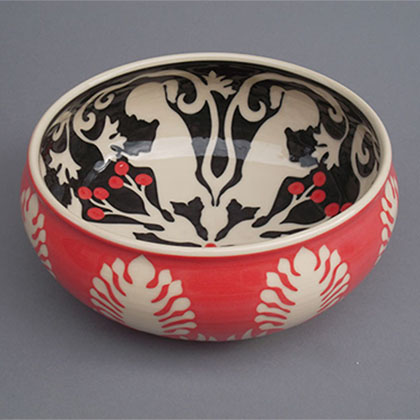 red ceramic bowl with hand-cut white flower patterns and a black interior of a girl on her cell phone