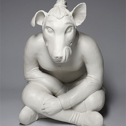 white ceramic sculpture of a dog  with a man bun sitting crisscross like a human and a tongue sticking up, licking its lips as though it is looking at something yummy to eat