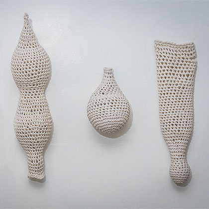 four white cotton yarn objects that were crochet to resemble various body types, shapes, and sizes