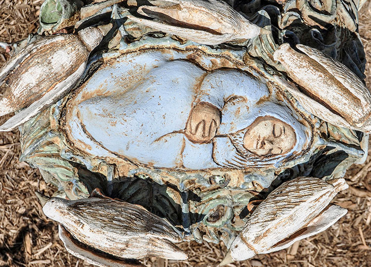 detail of the top of the sculpture's head with a sleeping baby and surrounding birds