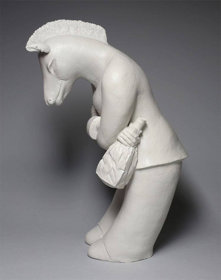 white ceramic sculpture of a horse standing like a human, slightly bowed, and holding a brown bag with an alcoholic beverage inside