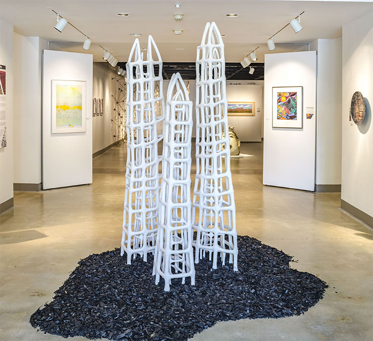 three white ceramic stoneware of tower-like cages inside cages on mulch