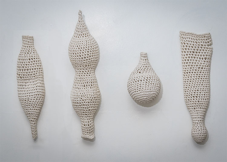 four white cotton yarn objects that were crochet to resemble various body types, shapes, and sizes