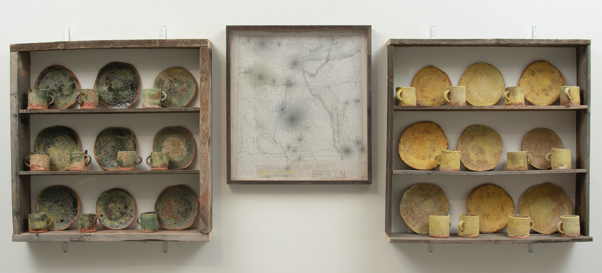wo shelving units that holds a full set of yellow dishes on the right side while a full set of green dishes on the right side with a framed map in the middle of both units.