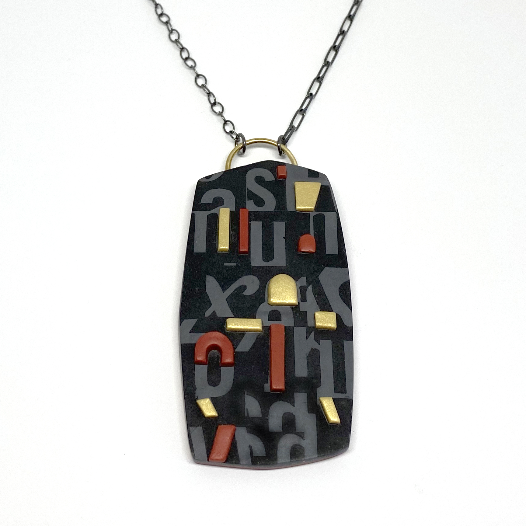 black pendent with gray letters painted on it. Maroon and gold shaped protrude out of the pendent.