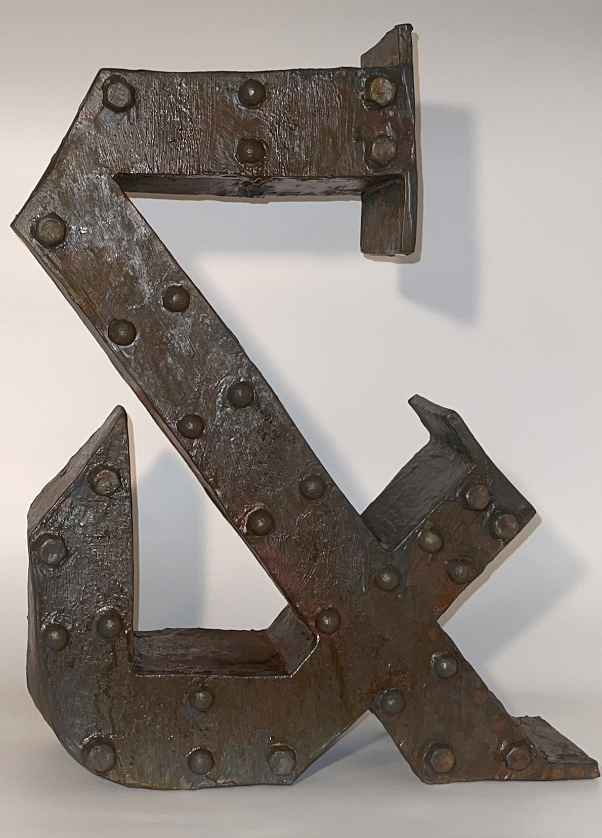 sculpture of an & sign. It is a dark brown color and looks very industrial. It has belts and knobs on it.