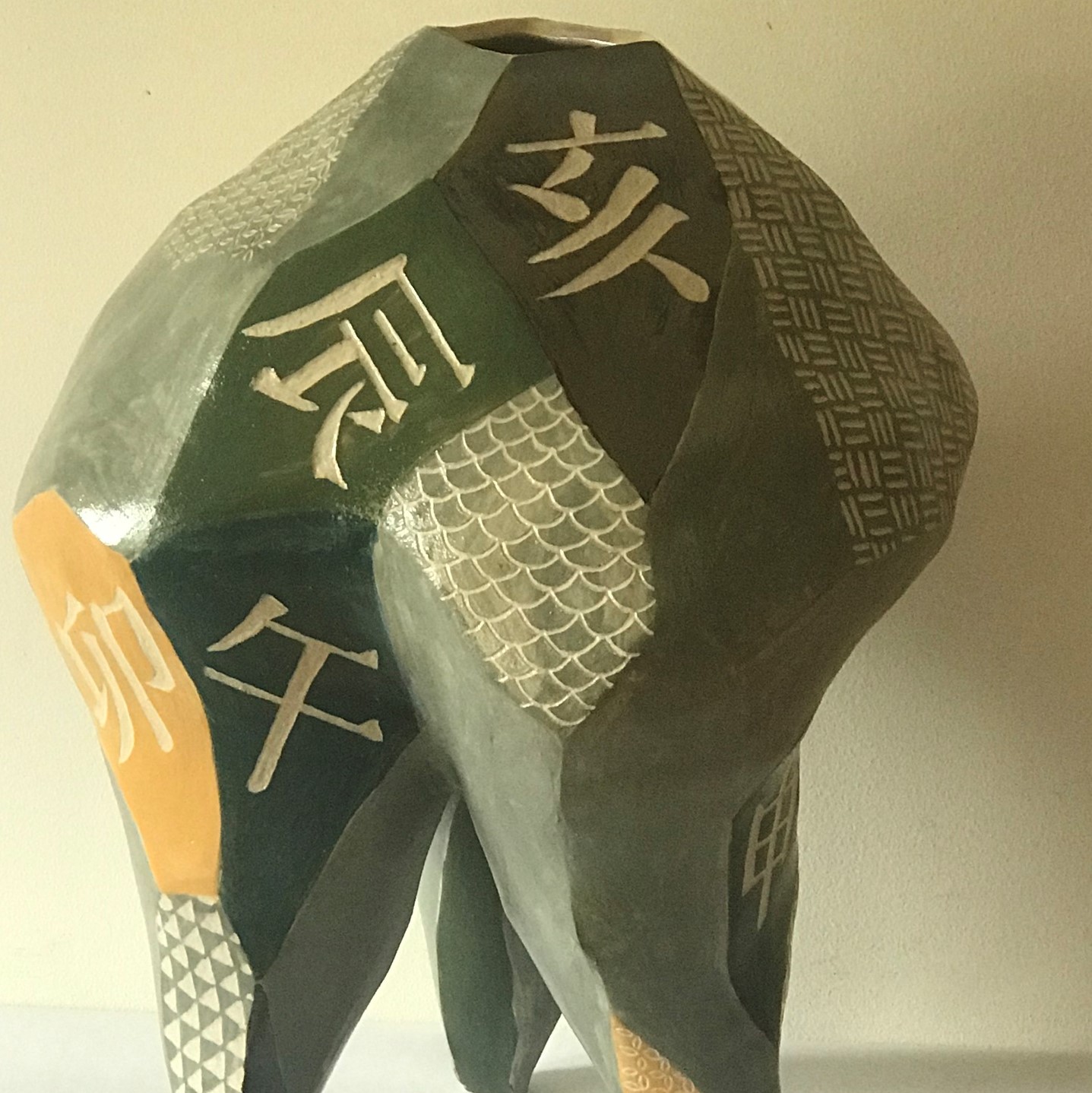 a ceramic piece that stands on four legs with scales, other patterns, and Chinese characters that state the different names Chinese zodiac signs.