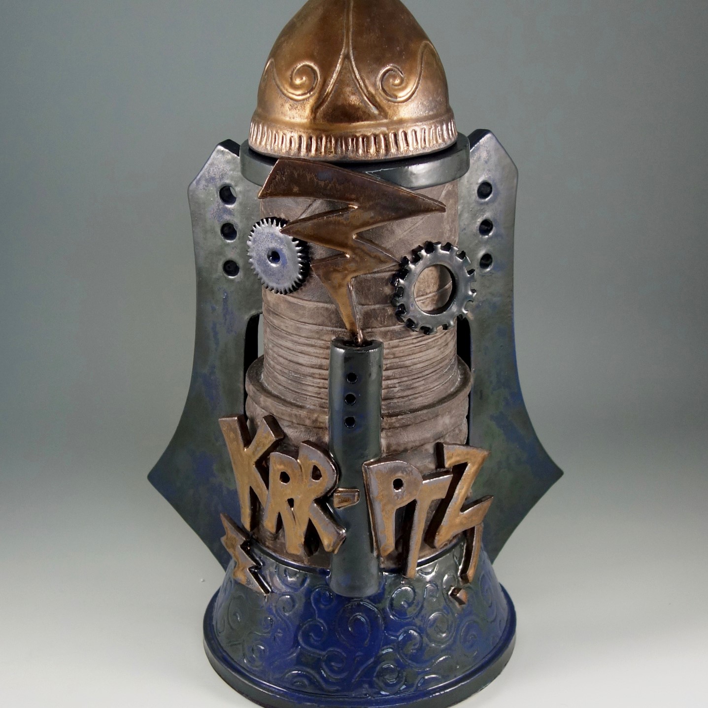  dark blue, metal, and bronze colored, futuristic style cookie jar with the word "KRR-PTZ" on the front with metal cogs and bronzed lightening strikes.