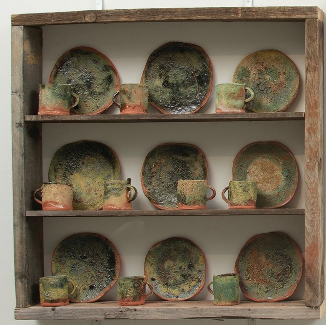 wo shelving units that holds a full set of yellow dishes on the right side while a full set of green dishes on the right side with a framed map in the middle of both units.