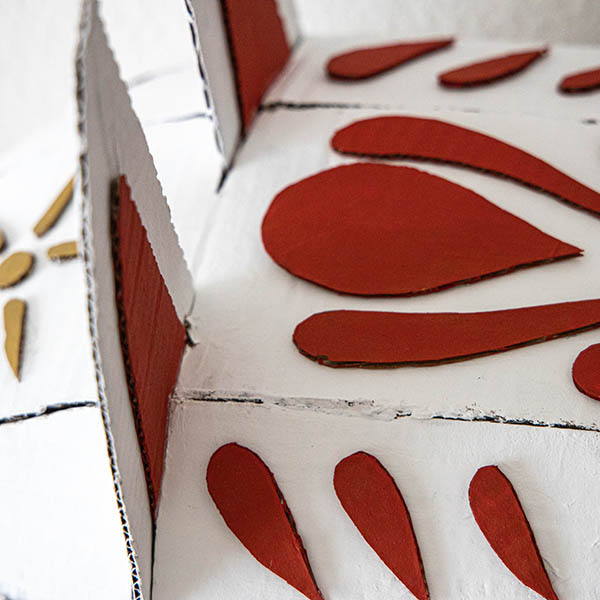 detail of White cardboard sculpture of a wolf head, Details are portrayed using orange cardboard.