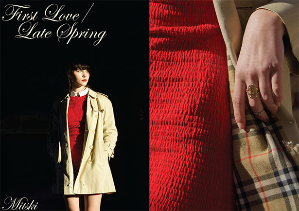 magazine spread. on one side there is a young woman in a red dress standing in a dark area. On other side is a close up of her dress and plaid coat. Cursive text on left side reads 'First Love/ Late Spring. Mitski'