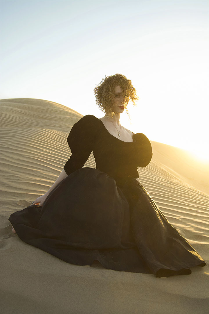 digital photography of a lady in a black dress sitting in the desert