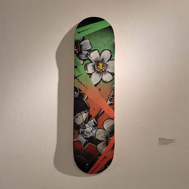Skoolz Out Fundraiser Board, image is a skateboard with colorful paintings of a flower and a girl