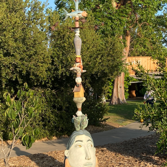 Full Moon: Image description: Statue containing a person, cactus, animals, birds, and buildings