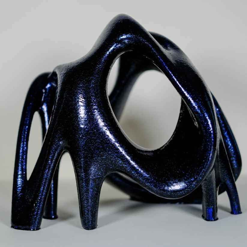 Oblate: IMage description: curved geometric statue with black and blue shimmer