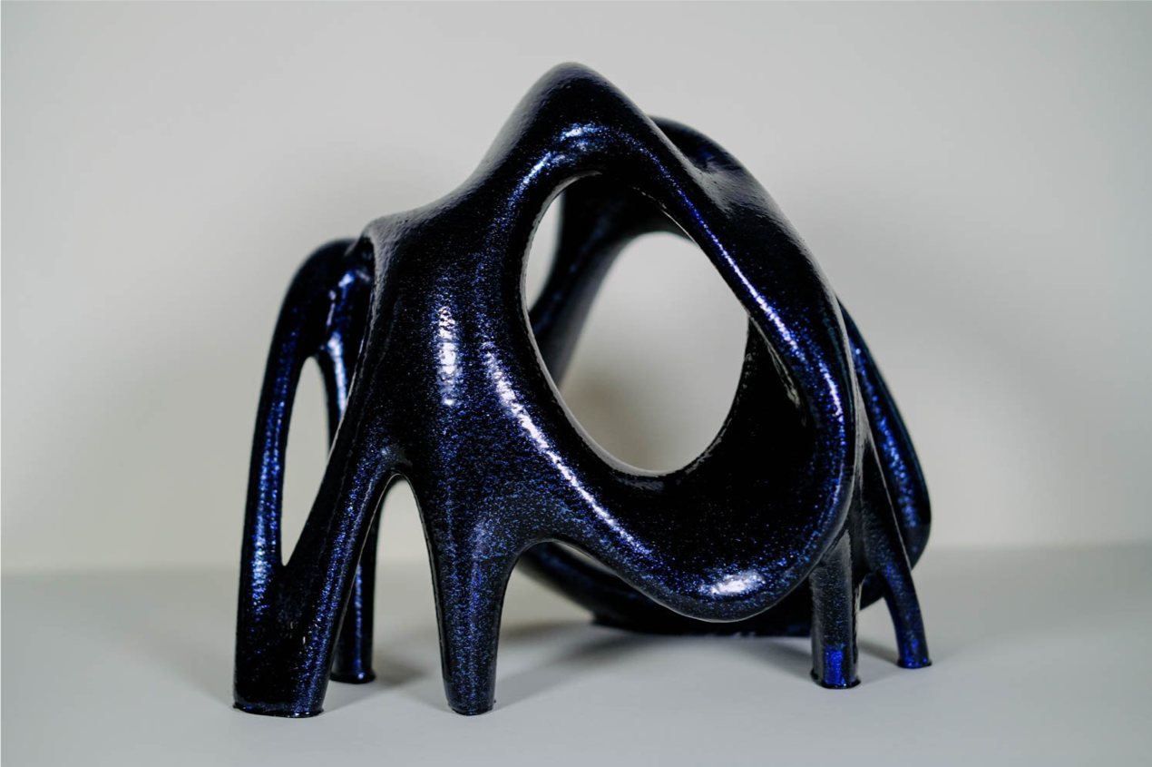 Oblate: IMage description: curved geometric statue with black and blue shimmer