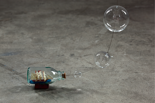 a little ship in a glass container with glass sphere above it