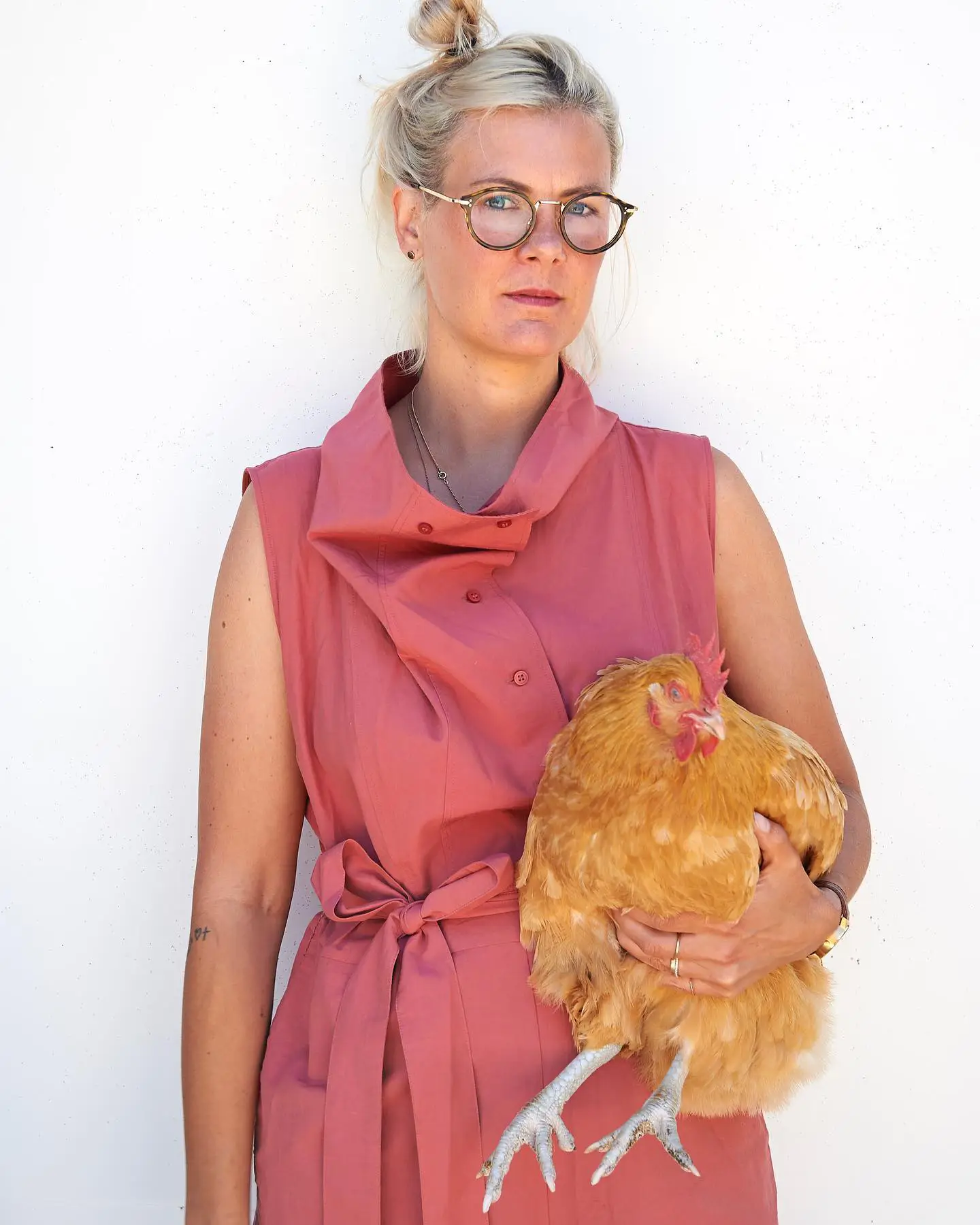 Artist Nike Schröder posing with a chicken in her arms.