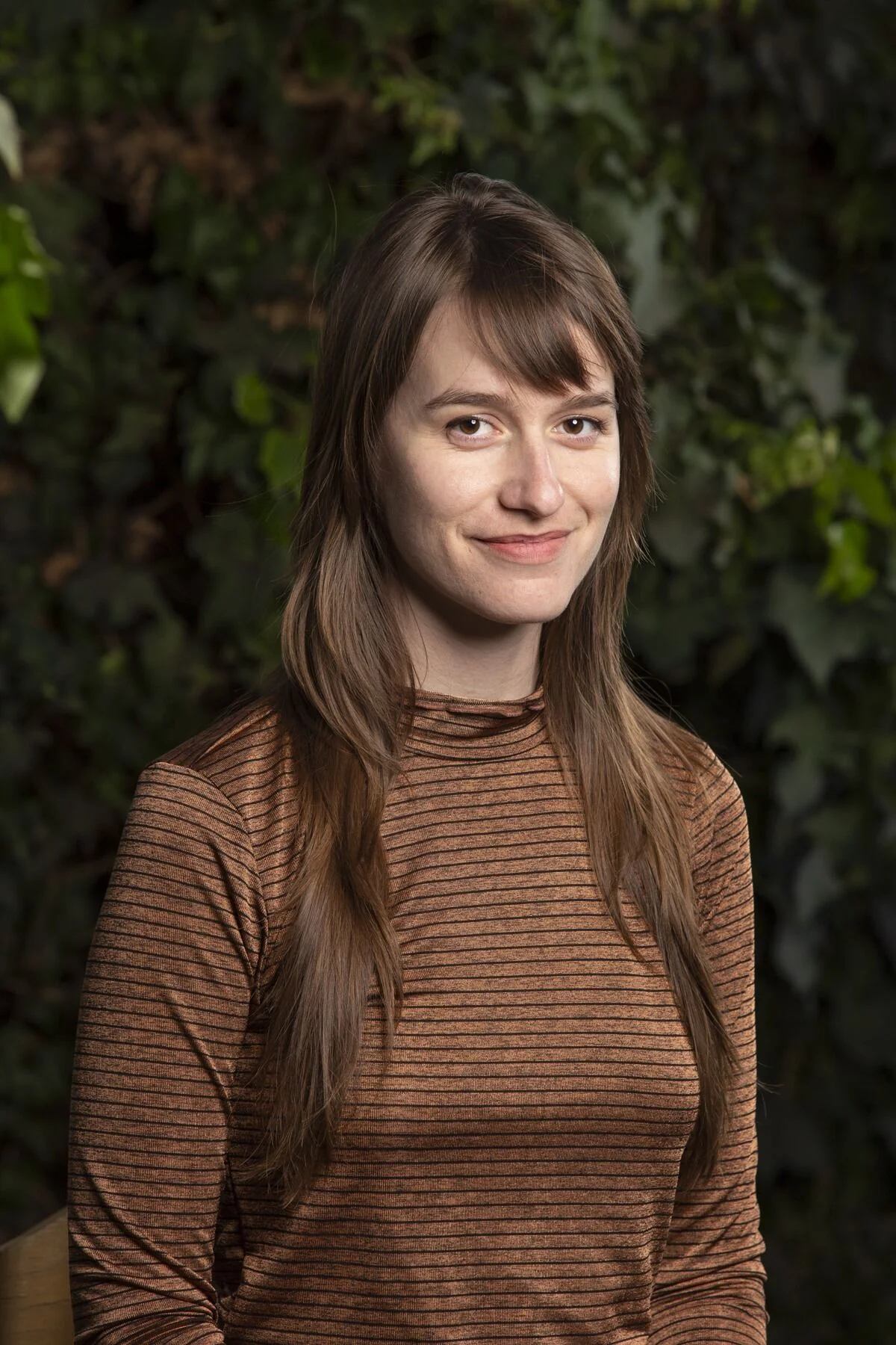 Smiling woman with long,dark, straight hair posing in front of a camera.