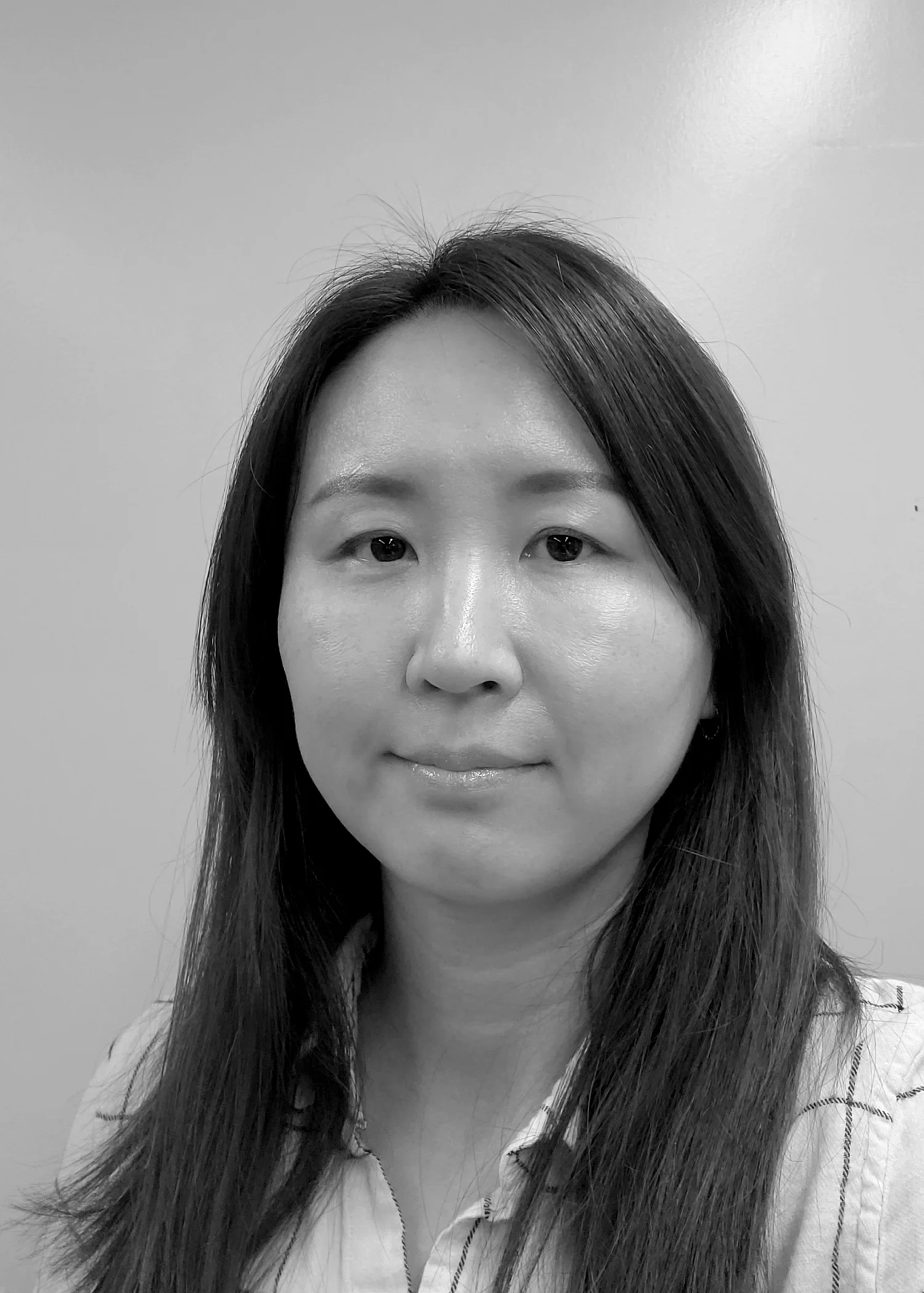 A woman with long dark hair smiles at the camera with a black and white filter.