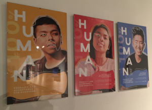  three posters, one blue, on yellow, and one red, each featuring a portrait of a person and the words 'human'