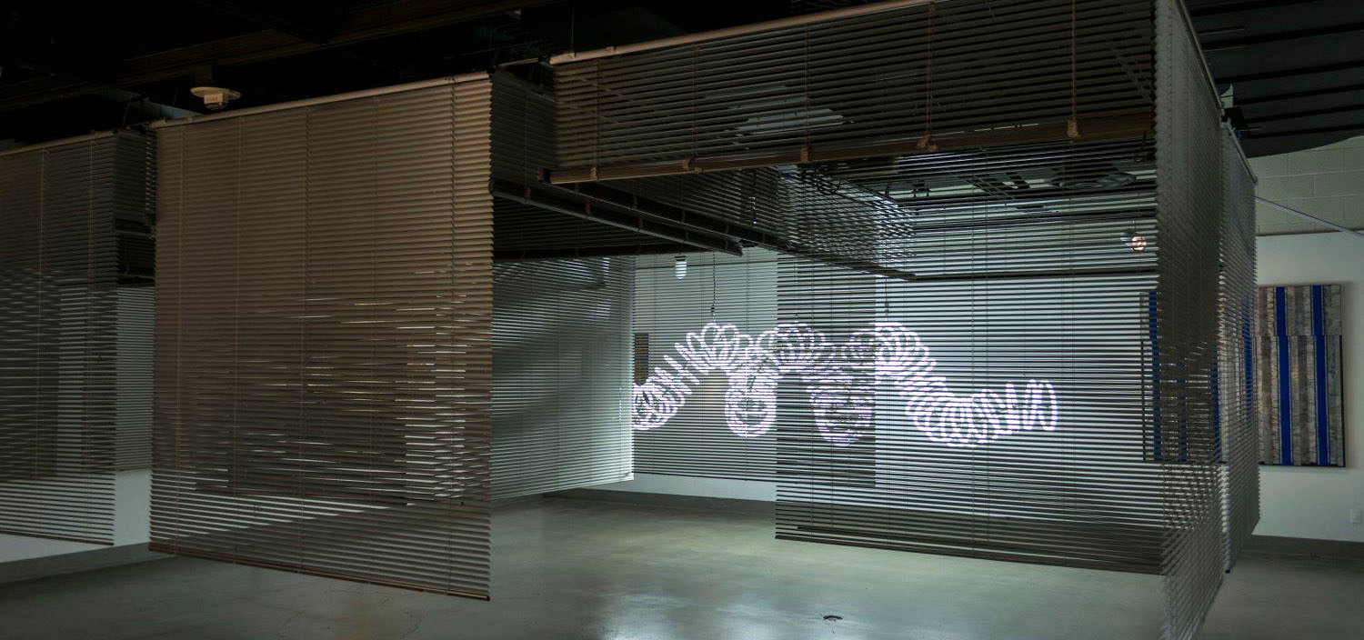 gallery space featuring a glowing sculpture that is the shape of a slinky