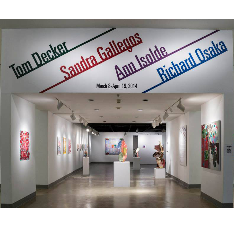 Title wall of gallery with artist names in green, blue, red, and purple: Ann Isolde, Tom Decker, Sandra Gallegos, Richard Osaka