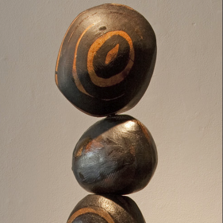 image of three brown clay balls stacked on top of each other. The top one has an orange swirl on it.