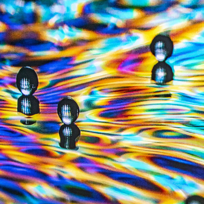 close up image of a few rain drops about to hit water. The water is rippling, and the image is made up of saturated hues of purple, orange, blue, and pink.
