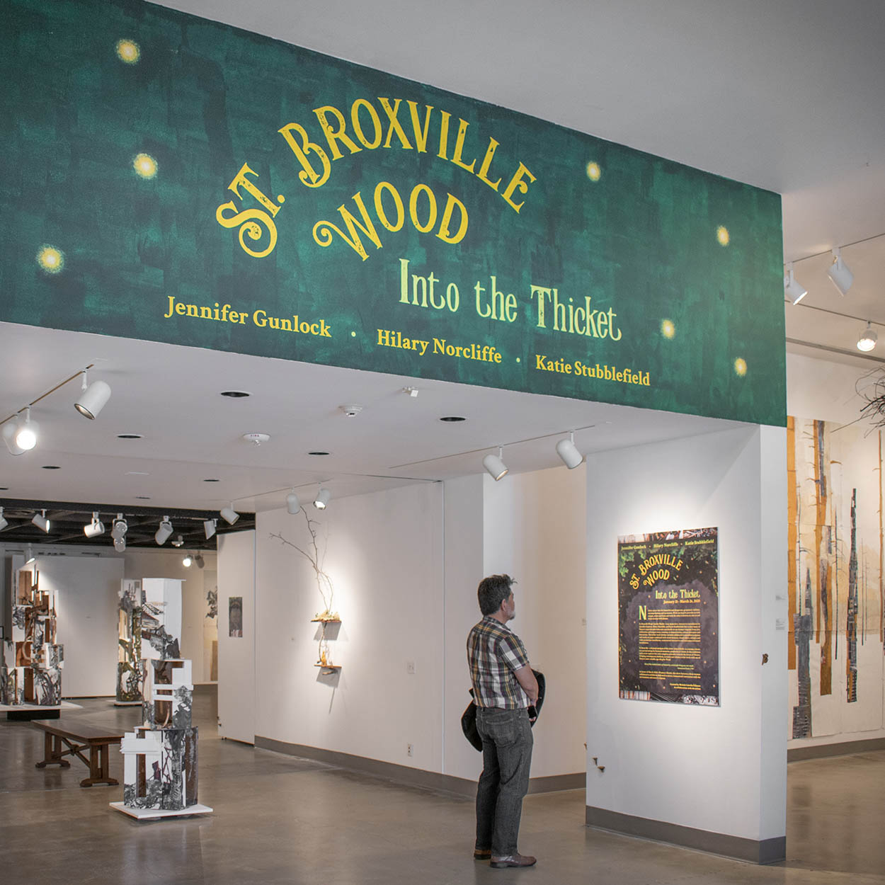 image of gallery title wall painted green with yellow letters: St. Broxville Wood: Into the Thicket. 
