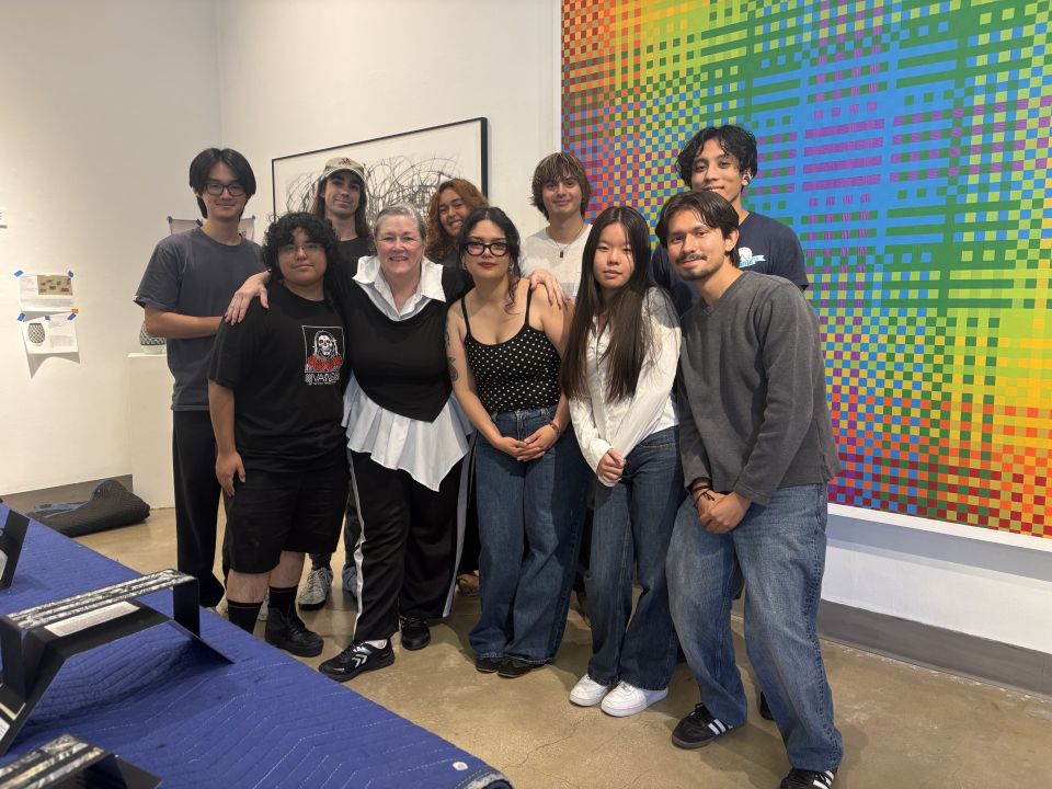 Group photo of entire team standing infront of a large artwork by Megan Geckler