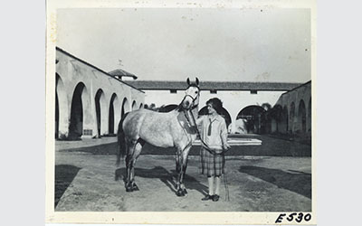 Historic photograph of a person standing with an Arabian horse at the W.K. Kellogg Ranch