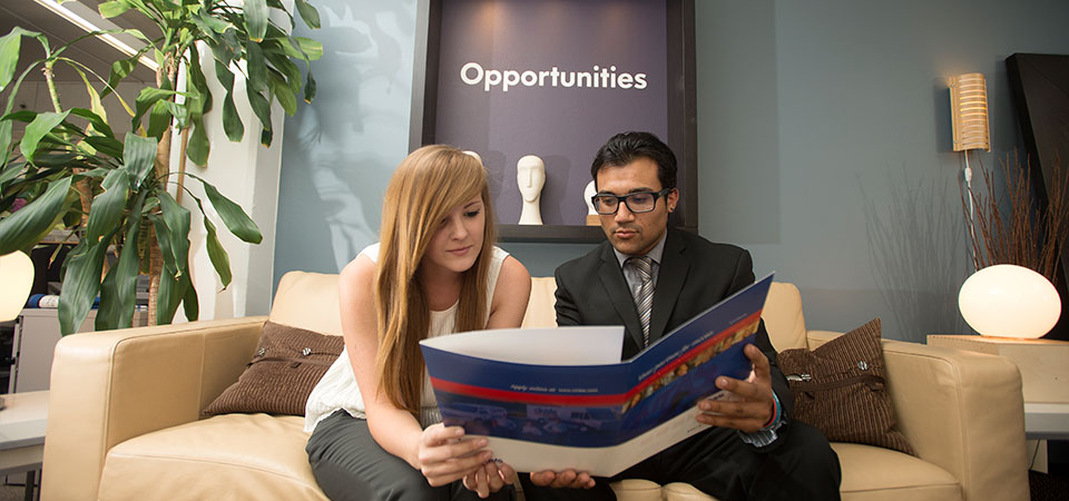 Students looking over a folder in a room with the word opportunities on the wall