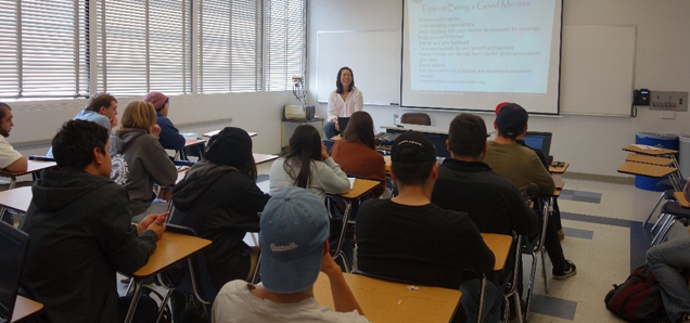 Faculty sitting in front of full classroom of students