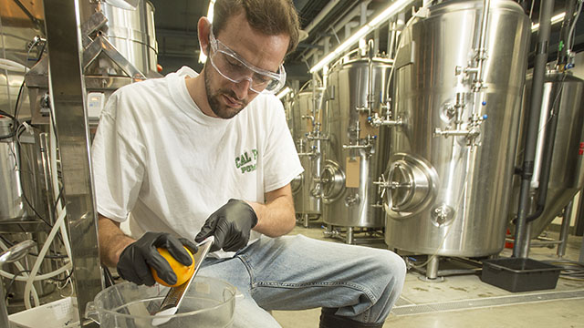 Koby Harris zests an orange for an orange wheat beer brewed at Innovation Brew Works.