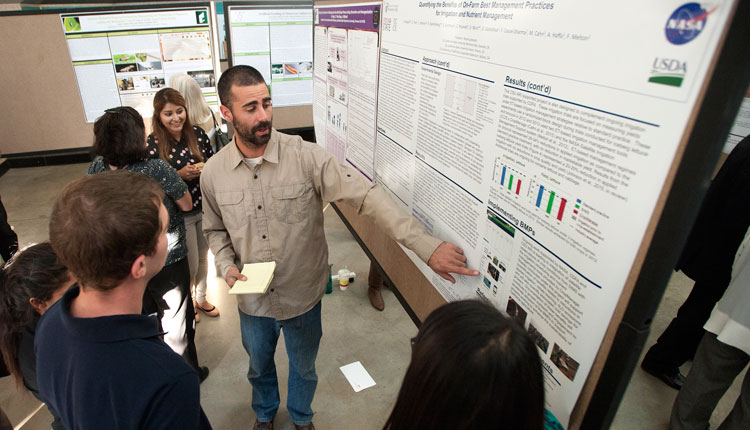 A student presents his research at the poster session portion of the Agricultural Research Institute Showcase.