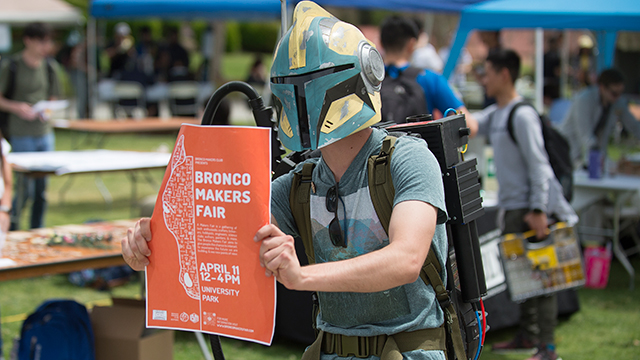 Tucker Dunbar tries to recruit passersby to the Bronco Makers Fair while wearing a Star Wars helmet and a Ghostbusters Proton Pack.