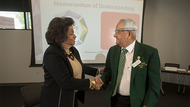 President Soraya M. Coley shakes hands with alumnus Ganpat Patel, the founder of Ganpat University in India.
