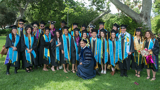 Students from the College of Science post with Steve Alas during the 2019 commencement cermonies.