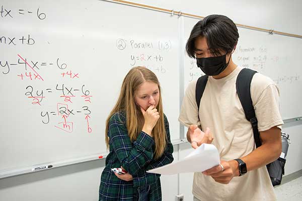 Jamie Thomas, a math grad student, helps Bronco Scholar Ethan Luong with a math problem during Bronco Scholars math class.